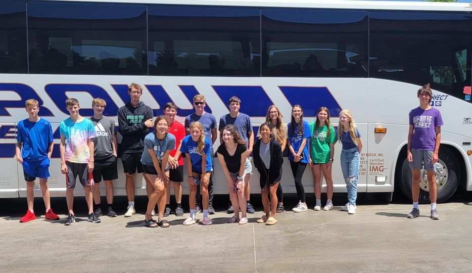 Students posing in front of charter bus