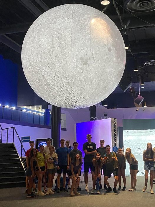 students standing under moon exhibit